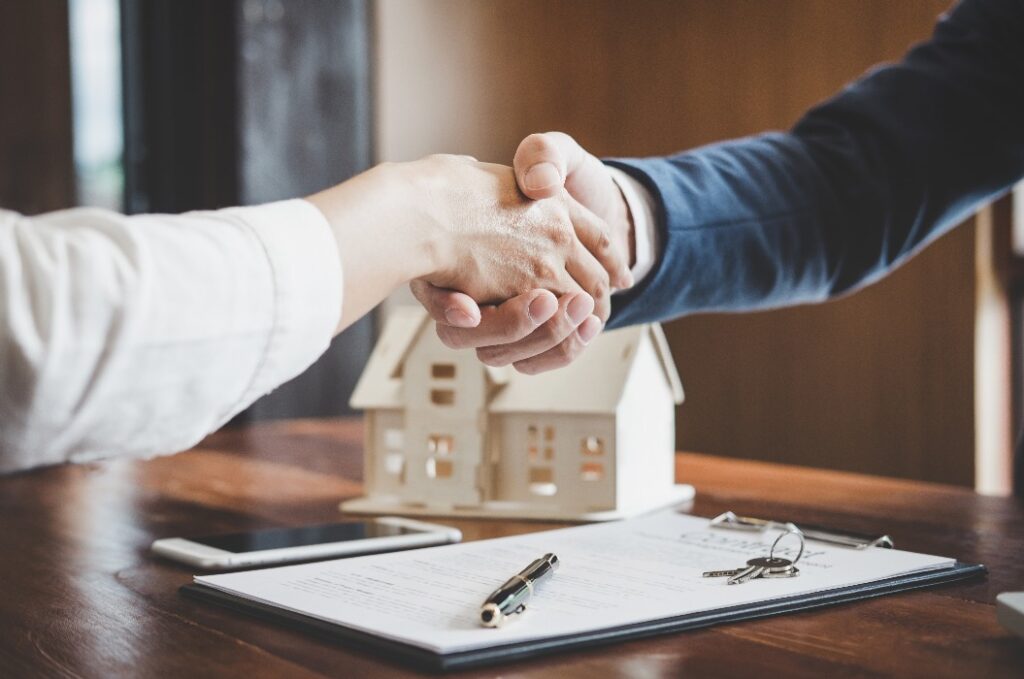Estate agent and customer shaking hands after finished contract after about home insurance and investment loan