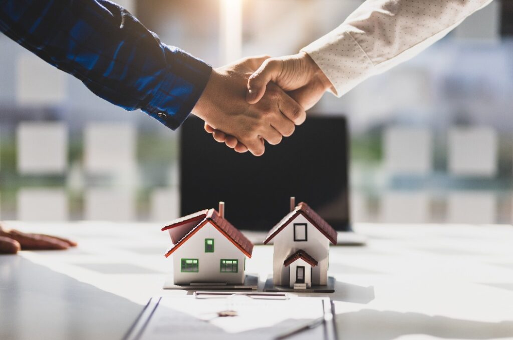 Real estate agents shake hands after the signing of the contract agreement is complete.